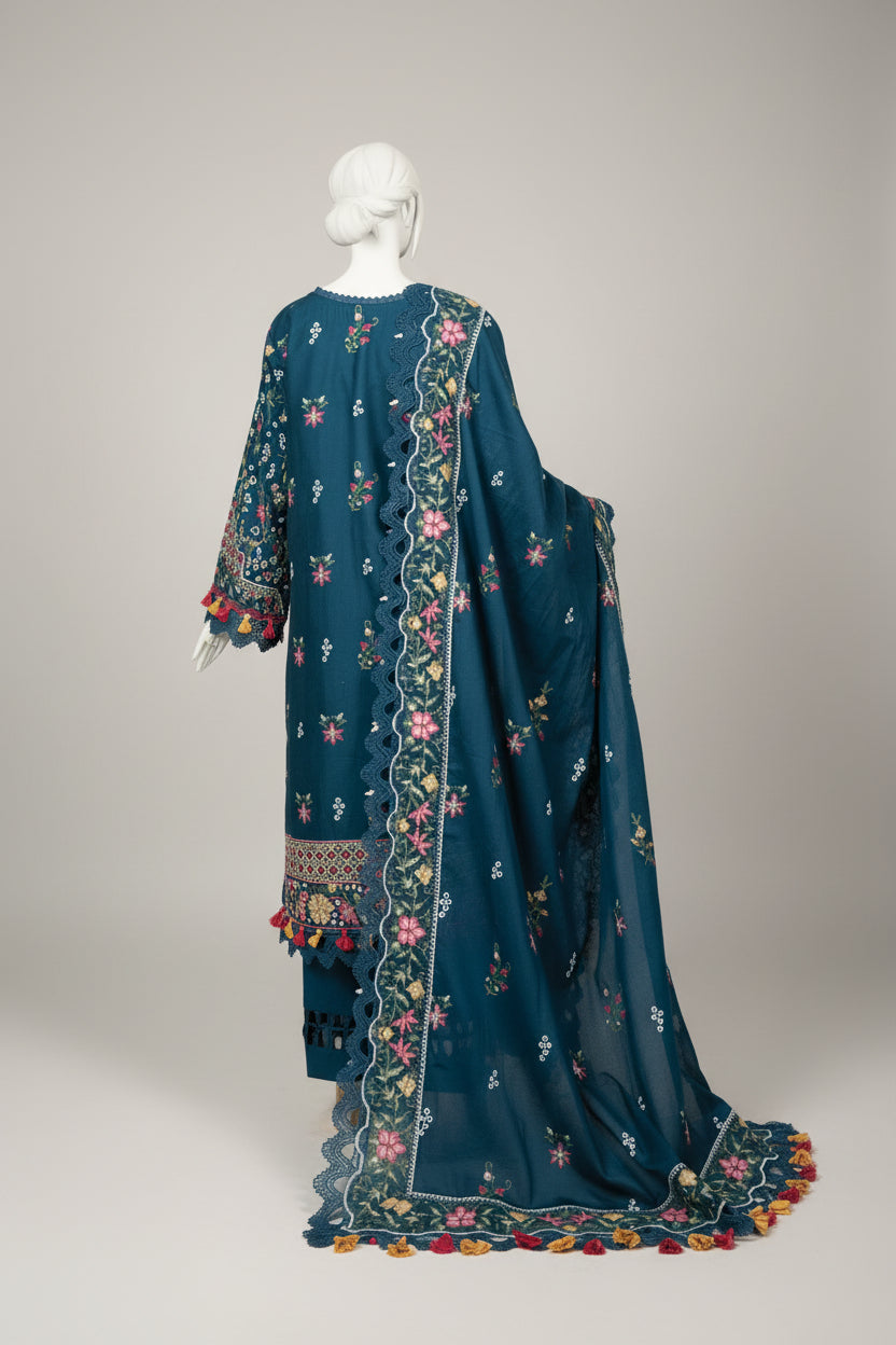 Blue embroidered dress on a mannequin in a room with white furniture and large windows.