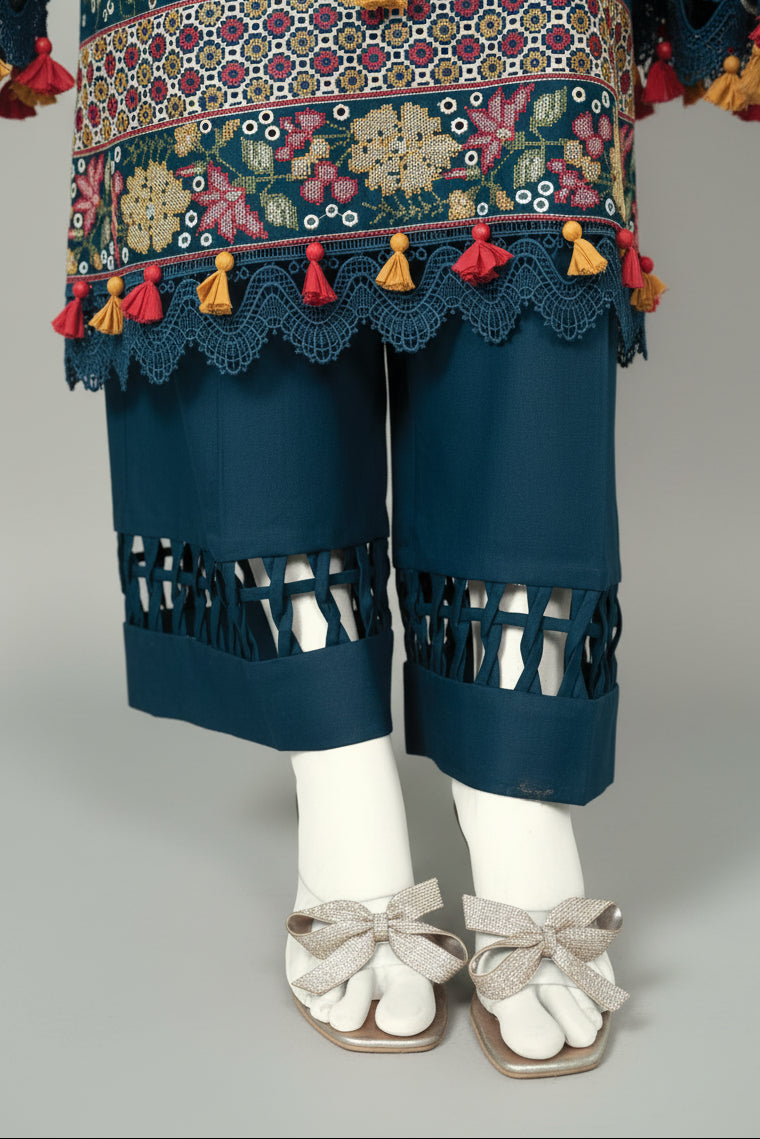 Traditional embroidered outfit with colorful tassels and cut-out pants on a checkered floor.