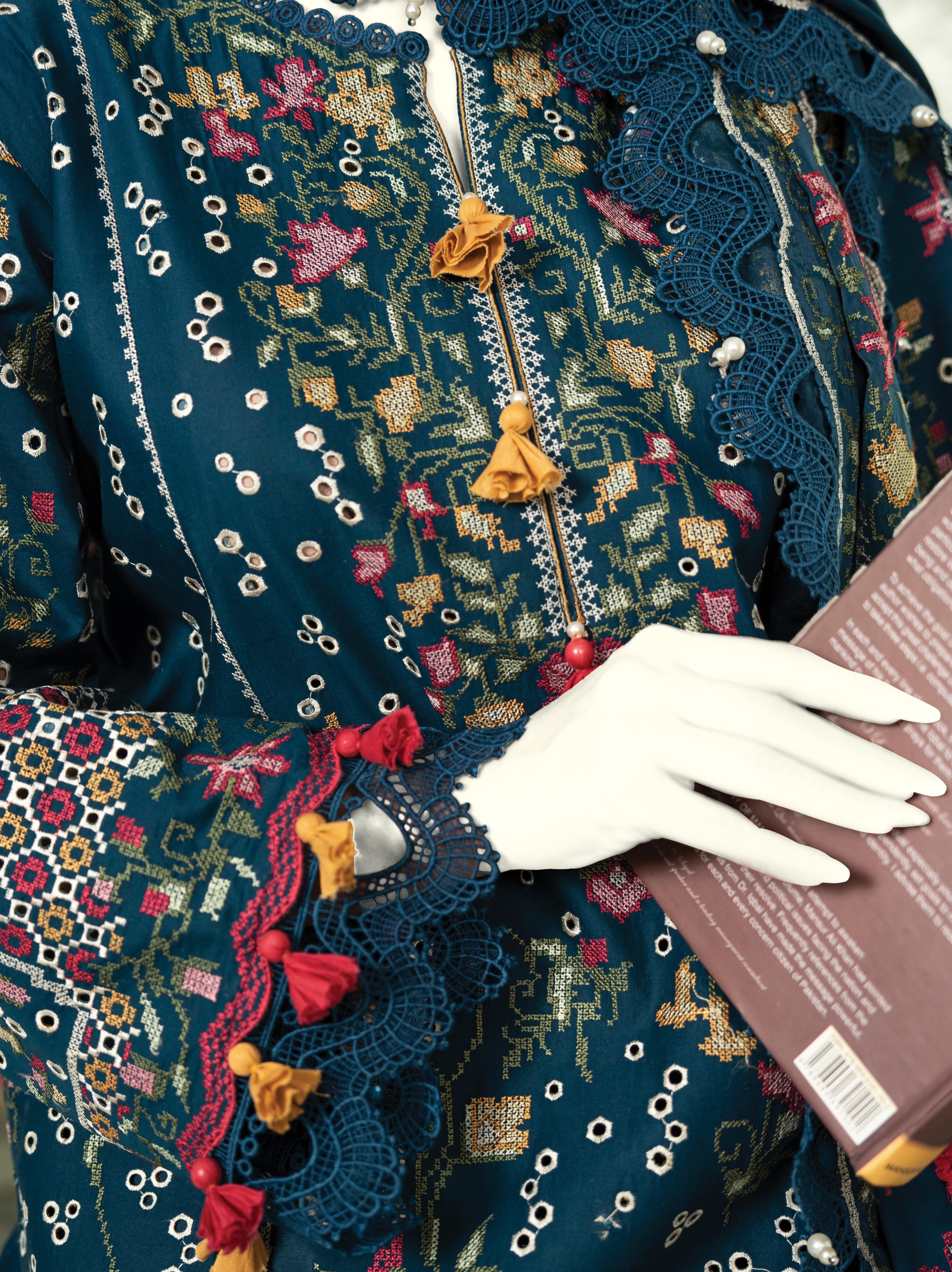Close-up of a person wearing a detailed embroidered garment with a white glove holding a book.