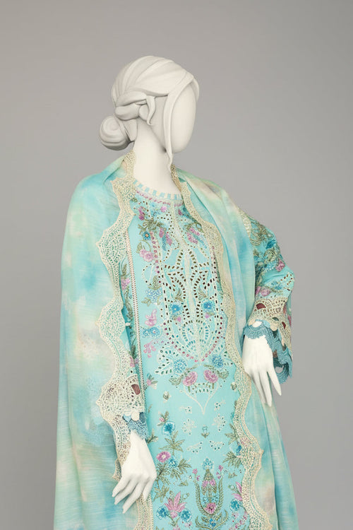 Mannequin wearing a light blue embroidered dress with a matching shawl in a room with checkered floor.