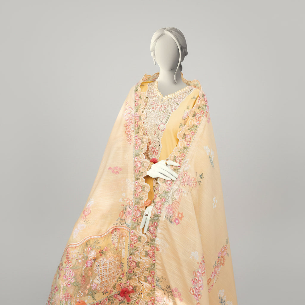 Mannequin wearing a floral embroidered yellow outfit in an outdoor setting with plants and flowers.