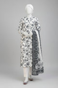 A three-piece women's salwar kameez suit set displayed on a mannequin in an outdoor courtyard. The set features an off-white/cream base with black floral and paisley block prints, including a long kurta, matching trousers, and a dupatta with ornate borders.