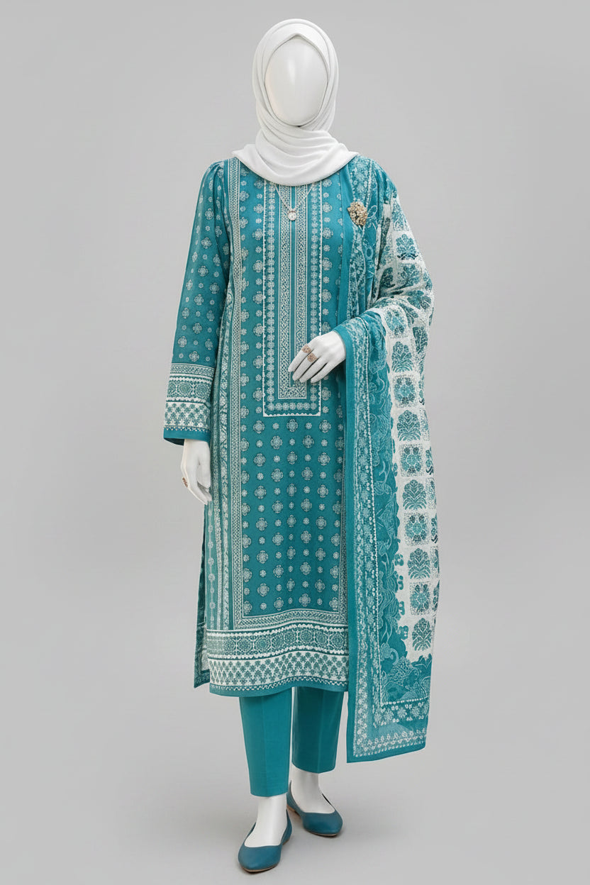 A woman wearing a teal and white printed three-piece traditional outfit with a matching dupatta, standing in front of an ornate courtyard with arches.
