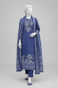 A blue three-piece traditional outfit displayed on a white mannequin, featuring a kurta with white embroidery, matching pants, and a coordinating dupatta, set against an outdoor garden event backdrop with floral arrangements and string lights.