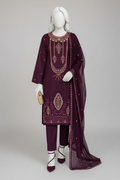A three-piece women's salwar kameez suit in deep purple, displayed on a mannequin in an ornate, traditional Indian palace courtyard. The set includes a heavily embroidered kameez tunic, matching trousers, and a sheer embroidered dupatta.