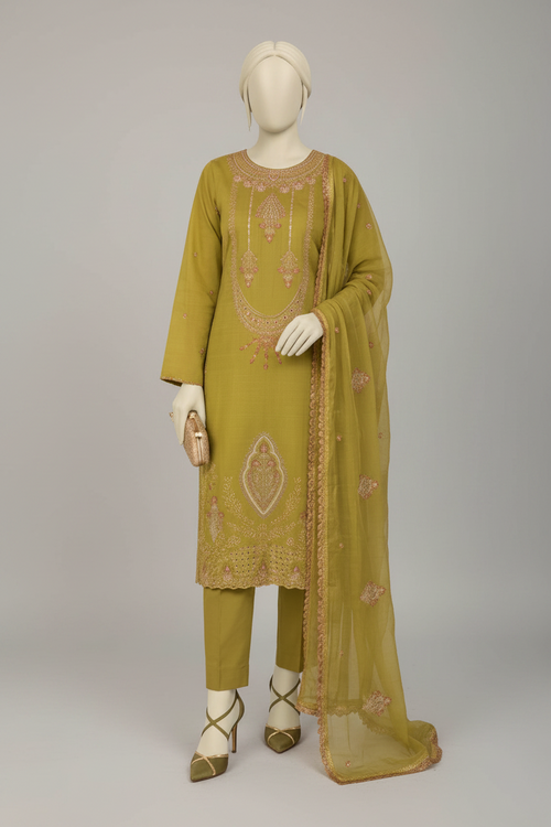 A three-piece olive green ethnic suit displayed on mannequins in an ornate indoor setting with hanging swings and carved arches. The set includes a long kurta with pink and gold embroidery, matching trousers, and a sheer dupatta.