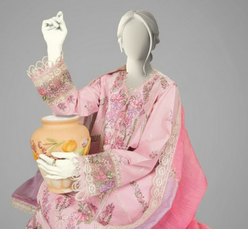 Mannequin wearing a pink floral dress holding a decorative vase against a gray background