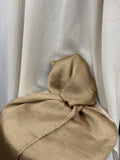 A draped piece of shimmering champagne-gold fabric, likely silk or satin, arranged in soft folds against a backdrop of white draped fabric.