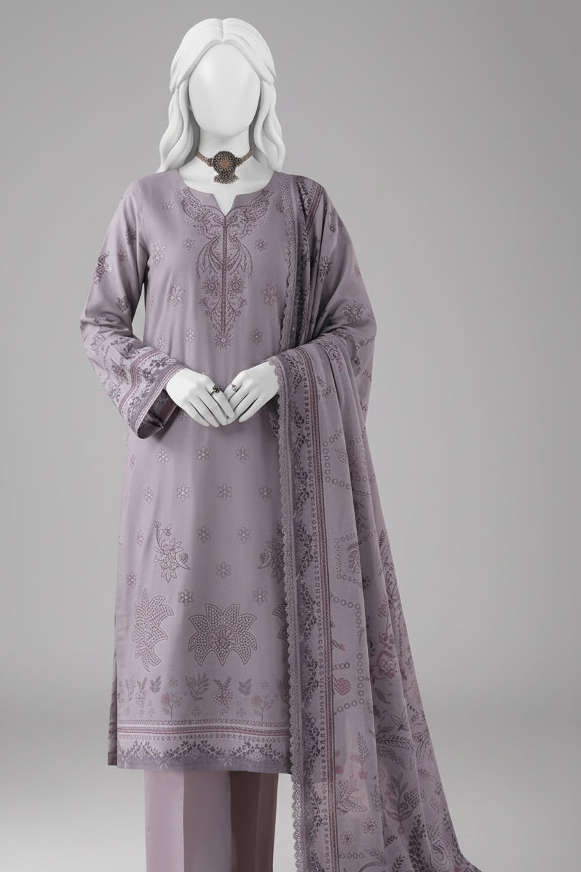 A three-piece women's salwar kameez suit in a dusty lavender-gray color, displayed on a white mannequin. The set includes an embroidered long kurta, matching trousers, and a dupatta with floral patterns, set against a soft pink background with decorative ceramic vases.