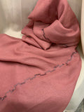 A dusty pink textured fabric, likely a shawl or scarf, draped over a white chair with a decorative zigzag border of small silver rhinestones.