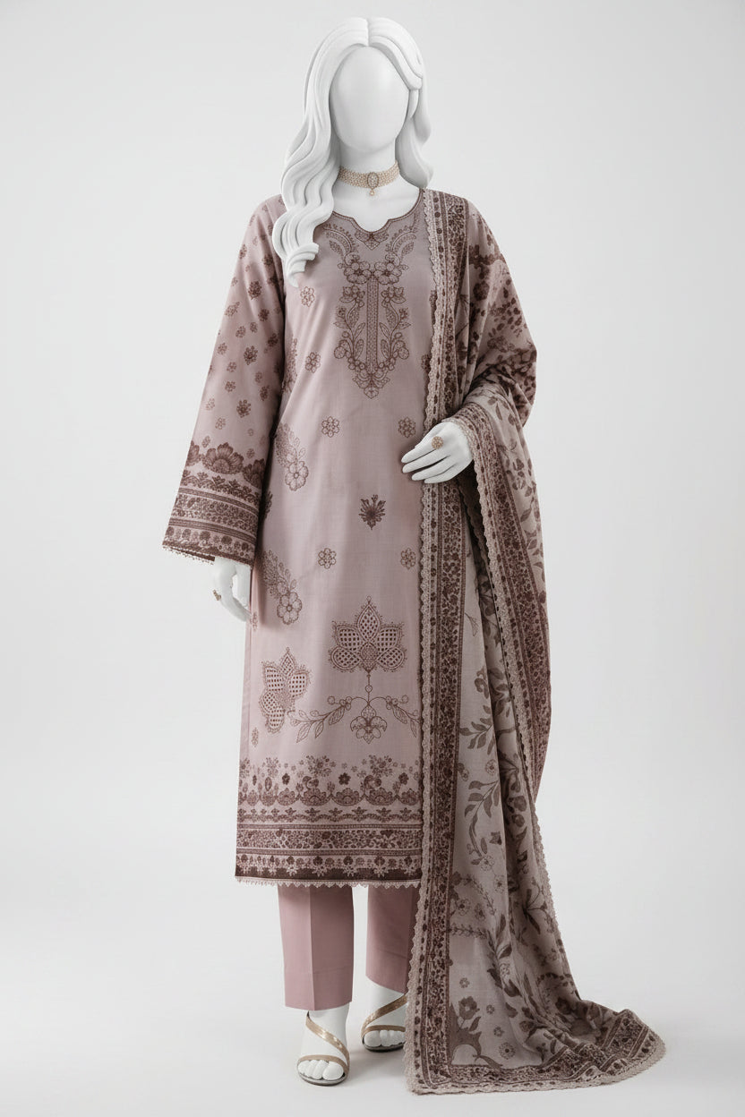 A three-piece women's salwar kameez suit set in a dusty mauve color with brown printed embroidery, displayed on a white mannequin. The set includes a long kurta with detailed embroidery, matching trousers, and a coordinating dupatta, set against a soft pink background with decorative props.
