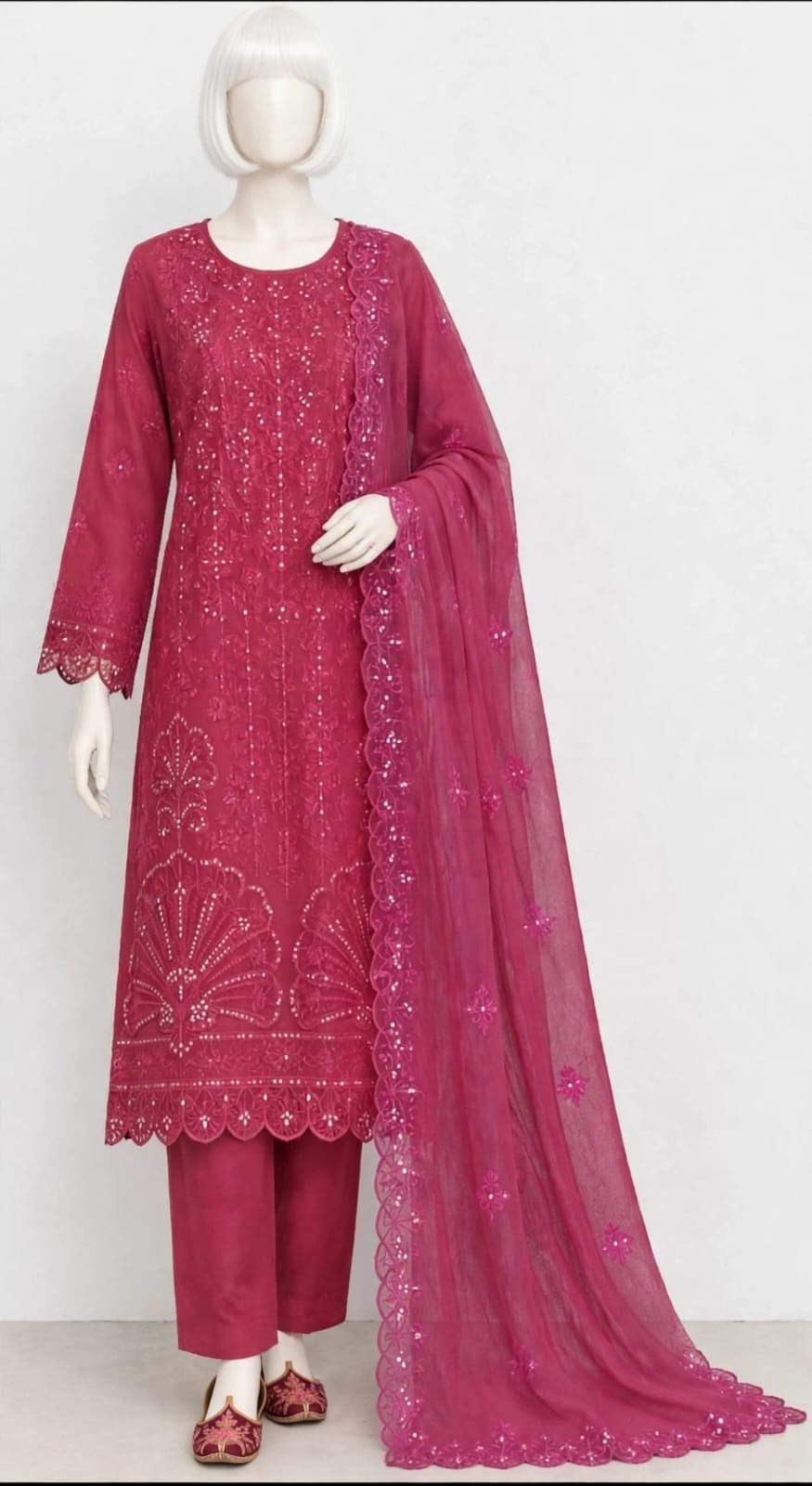 A magenta pink ethnic suit set displayed on a female mannequin, featuring a long-sleeved embroidered kurta, matching trousers, and a sheer embroidered dupatta.