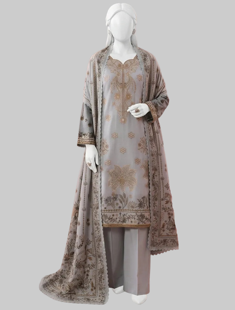 A three-piece women's traditional outfit displayed on a white mannequin, featuring a light gray kurta with gold embroidery, matching gray trousers, and a sheer gray dupatta with gold borders, set against a pink background with a pink armchair.