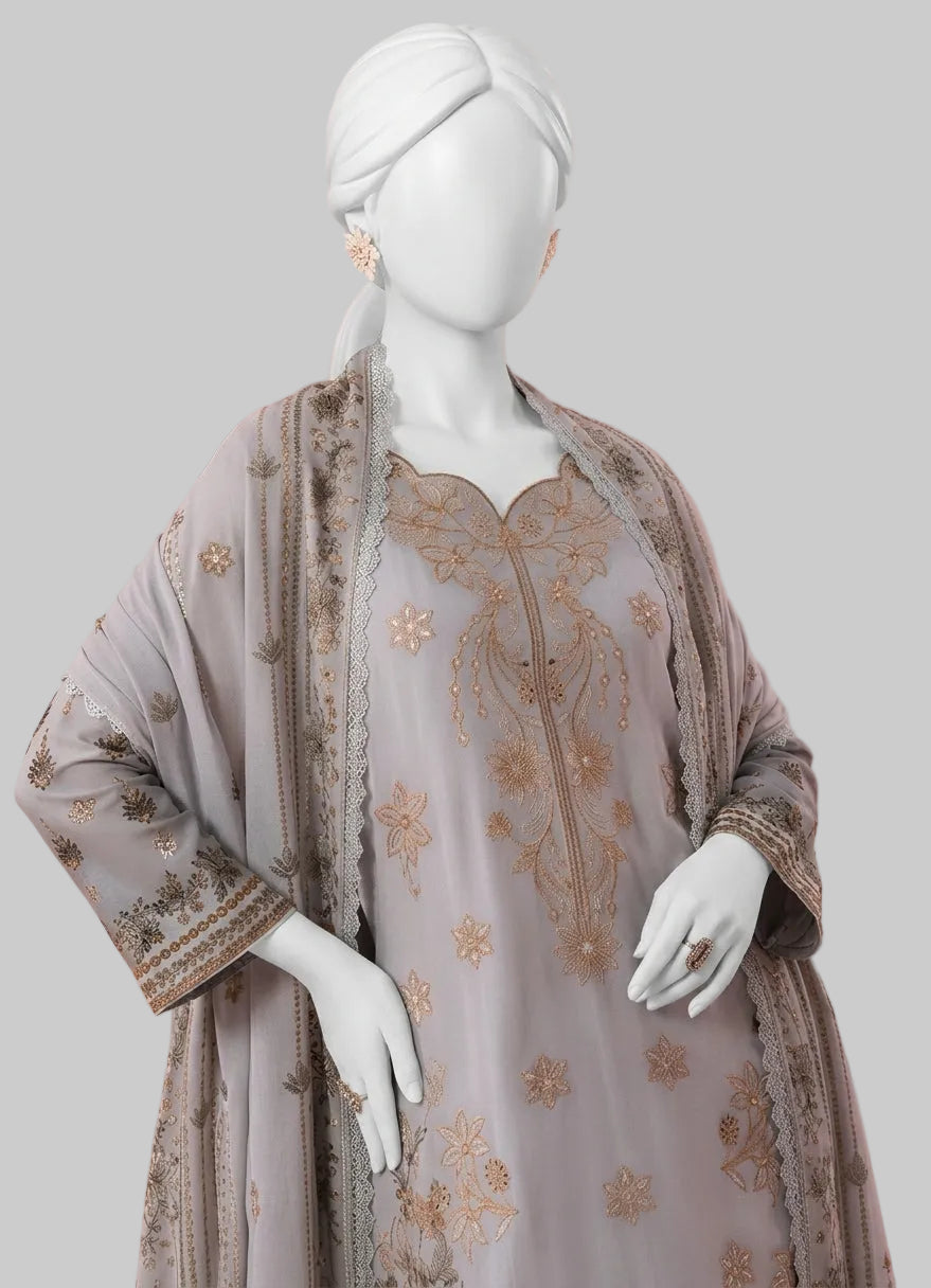 A three-piece women's ethnic outfit displayed on a white mannequin, featuring a light grayish-blue kurta with gold floral embroidery, a matching embroidered dupatta, and a gray outer jacket with gold detailing, set against a solid pink background.