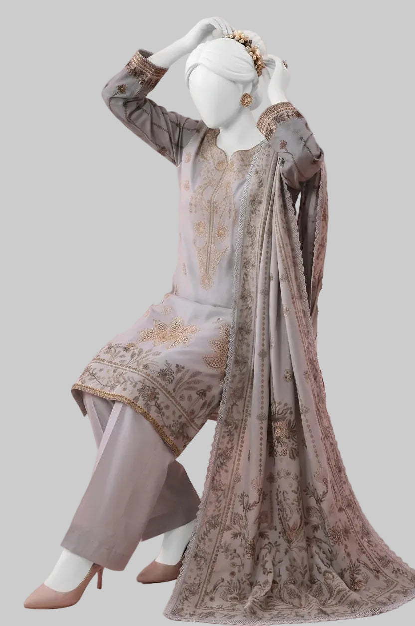 A mannequin dressed in a traditional South Asian outfit consisting of a light gray embroidered kurta, matching trousers, and a sheer dupatta with gold patterns, posed on a pink armchair against a solid pink background.