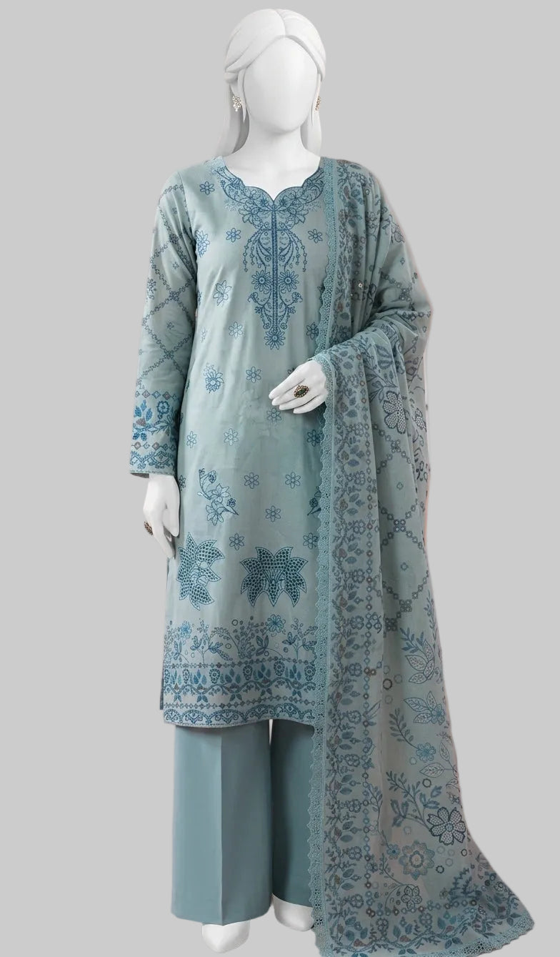 A three-piece women's traditional outfit displayed on a white mannequin, featuring a light blue-green kurta with blue floral embroidery, matching wide-leg trousers, and a sheer dupatta with a blue border, set against a solid pink background with a pink chair.