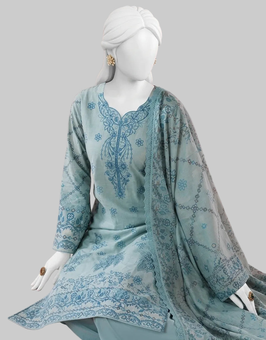 A light blue-green traditional women's outfit displayed on a white mannequin, featuring a printed tunic with a V-neck, long sleeves, and a matching sheer dupatta draped over the lap, set against a pink background with a pink chair.